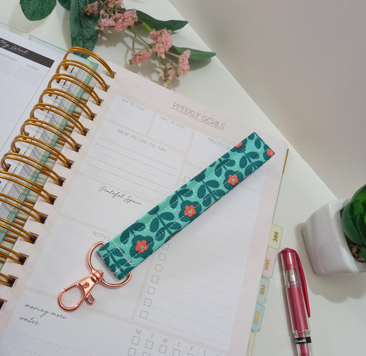 Our fabric wristlet in a green fabric with retro floral pattern with sewn in rose gold keyfob.